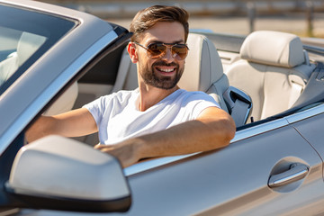 handsome bearded man looking away while sitting in cabriolet