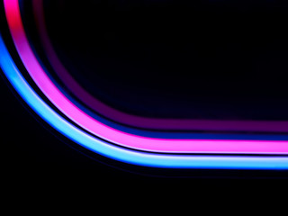 Neon blue, pink, viola tube lights glow on black backdrop, light design. Copy space. Trendy...