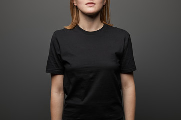 Fototapeta premium cropped view of woman in blank basic black t-shirt on black background