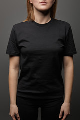Obraz premium cropped view of woman in blank basic black t-shirt on black background
