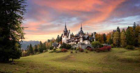 Panorama of Peles Castle, Romania. Beautiful famous royal castle and ornamental garden in Sinaia landmark of Carpathian Mountains in Europe at sunset. Former Home Of The Romanian Royal Family.  - obrazy, fototapety, plakaty