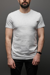 cropped view of bearded man in blank basic grey t-shirt on black background
