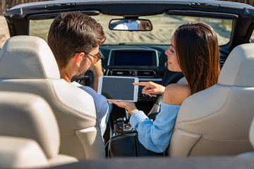 back view of multiethnic couple using digital tablet for navigating in convertible
