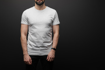 cropped view of bearded man in blank basic grey t-shirt isolated on black