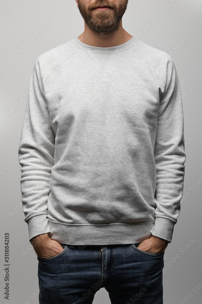 Wall mural partial view of bearded man in blank basic grey sweatshirt with hands in pockets isolated on grey - Wall murals