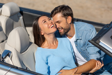 overhead view of young couple embracing in cabriolet