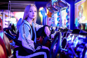 Beautiful blonde girl playing car racing on a slot machine. Girl gamer
