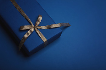 Gift box wrapped in classic blue paper with a gold ribbon. Color of the year 2020, Classic Blue. Copy space.