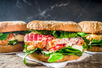 Various seafood and fish burgers assortment. Homemade healthy burger with grilled prawn, salmon, tuna, sea bass, fresh herbs, mozzarella cheese and baby spinach.