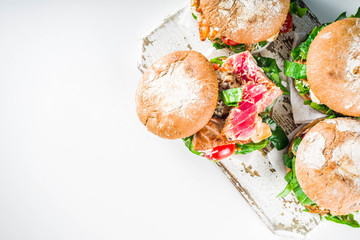 Various seafood and fish burgers assortment. Homemade healthy burger with grilled prawn, salmon, tuna, sea bass, fresh herbs, mozzarella cheese and baby spinach.