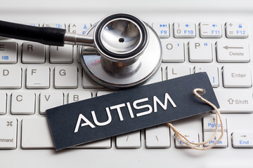 AUTISM word written on label with stethoscope and white keyboard