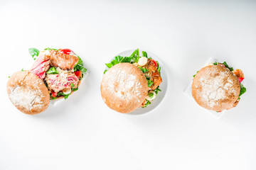 Various seafood and fish burgers assortment. Homemade healthy burger with grilled prawn, salmon, tuna, sea bass, fresh herbs, mozzarella cheese and baby spinach.