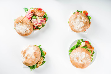 Various seafood and fish burgers assortment. Homemade healthy burger with grilled prawn, salmon, tuna, sea bass, fresh herbs, mozzarella cheese and baby spinach.