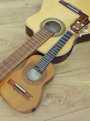 Fototapeta na wymiar Close-up of an acoustic guitar and a Brazilian string musical instrument: cavaquinho, on a wooden surface. The instruments are widely used to accompany samba and choro, two popular Brazilian rhythms. 