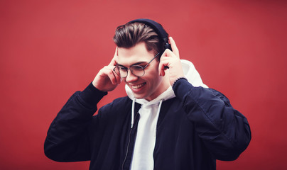 stylish man with headphones smiling in a black bomber jacket