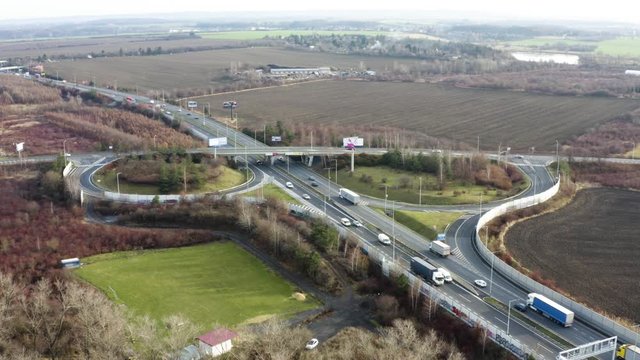 Aerial shot of transport infrastructure with cars during winter - village and nature in surroundings - (filmed by an officially certified pilot)