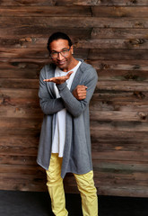 Vertical Portrait Young man with short-haired African-American glasses in ordinary clothes on a vintage wooden background in a home interior in a loft style. Standing right in front of the camera