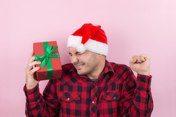 Happy surprised man in a red hat holding a gift with admiration on his face. Positive human...