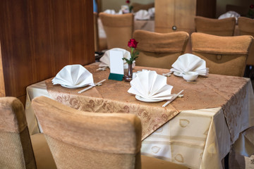 Table arrangement in chinese restaurant, brown-gold tablecloth, white napkin, white porcelain plate and chopsticks