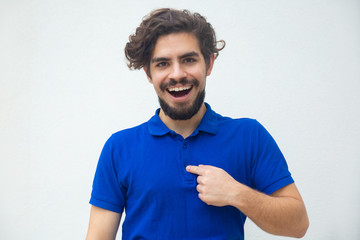 Surprised joyful guy pointing finger at himself with questioning face. Handsome bearded young man in blue casual t-shirt posing isolated over white background. Choice concept