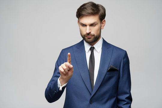 Businessman point finger at invisible screen, hand pushing touch screen, business man pressing digital virtual button isolated over grey background