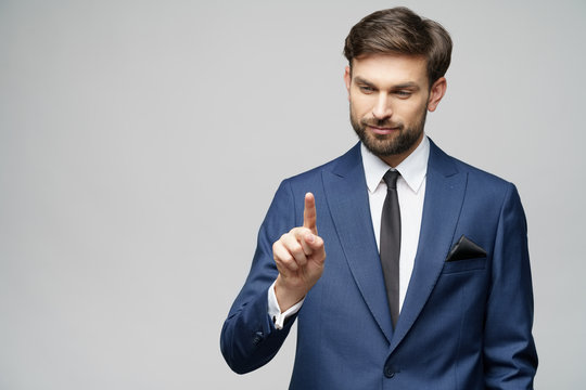 Businessman point finger at invisible screen, hand pushing touch screen, business man pressing digital virtual button isolated over grey background