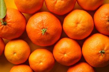 Orange tangerines on a yellow background close-up.