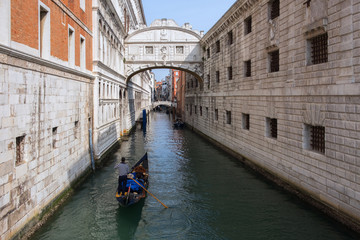Fototapeta premium Narrow canal between buildings, arched bridge, gondola on the water. Venice, Italy.