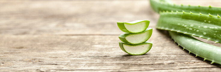 Pieces of aloe vera with pulp on a wooden background - obrazy, fototapety, plakaty