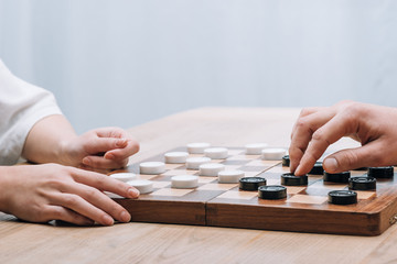 Cropped view of woman and man playing checkers at table
