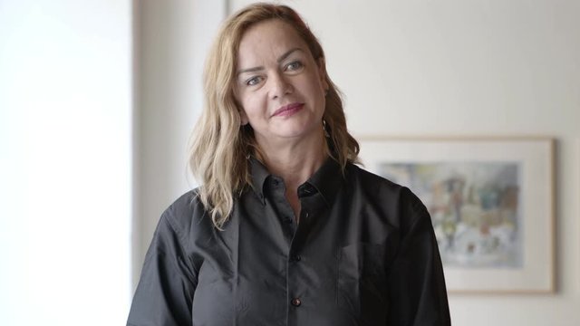 Front view of confident businesswoman smiling at camera. Portrait of beautiful middle aged businesswoman with hand on chin and smiling at camera. Business concept