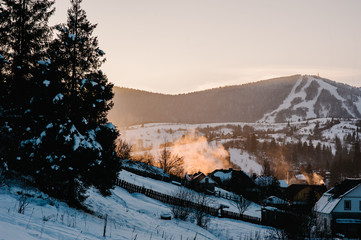Sunrise in winter mountains. Snowy village in the mountains. Place for text. Concept winter vacation and holidays. Snow-covered ski slopes.