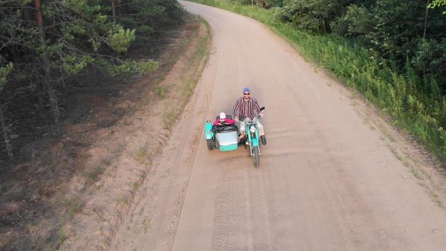 Sidecar retro motorcycle man and girl ride on unpaved road aerial high angle