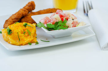 Breaded and herbed chicken breast fillet served with mashed carrots with potatoes  and  tomato salad with onions