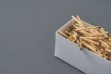 Full cardboard matchbox of many used matchsticks on dark concrete table on kitchen. Space for text