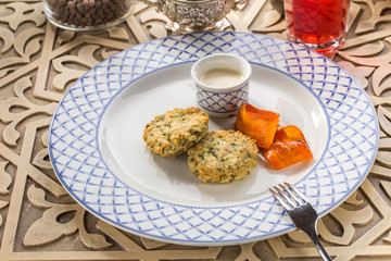 Zucchini potato pancakes with baked pepper and sour cream on oriental wooden table