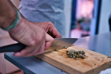 Chopping a fresh artichoke on a wooden kitchen board. Adult men hands. kitchen healthy life style