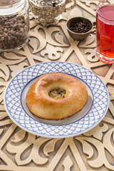 Fresh baked pasty with sesame seeds and glass of red drink on oriental wooden table