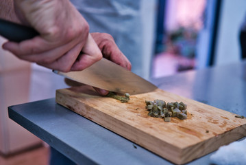 Chopping a fresh artichoke on a wooden kitchen board. Adult men hands.Chopping a fresh artichoke on a wooden kitchen board. Adult men hands. kitchen healthy life style