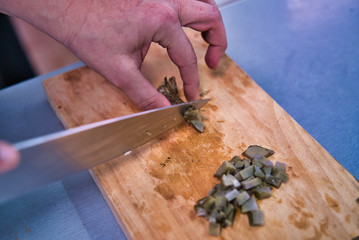 Chopping a fresh artichoke on a wooden kitchen board. Adult woman hands. kitchen healthy life style