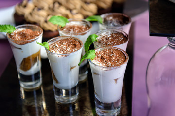 Sweet vanilla mousse with cocoa and mint, portioned dessert in glass cups. Catering, restaurant service.