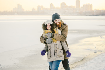 Young couple cheerfully flounders in snow. Between comic fight. Happy young couple hugs in winter snowy woods. Romantic lifestyle men and women in love. St. Valentine Day date Christmas hugging happy