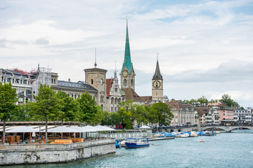 Fototapeta na wymiar View of the historic buildings and bridge of Zurich at the bank of Limmat River and Zurich lake, with landmark of Fraumünster Church clock tower and church tower of St. Peter Pfarrhaus