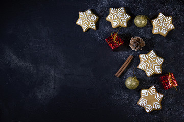 Christmas black background with gingerbread cookies and cinnamon. Copy space for text, table top view.