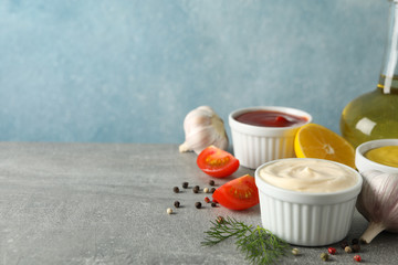 Set of different delicious sauces, garlic, cherry tomatoes, lemon on gray background, space for text