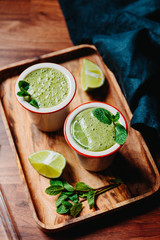 Two portions of green spinach smoothie with banana, lime and oat milk.