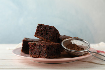 Plate with chocolate cake slices and strainer on wood table with towel, copy space