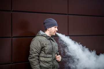 Vape man. Young handsome white caucasian bearded man in casual clothes smoking an electronic...
