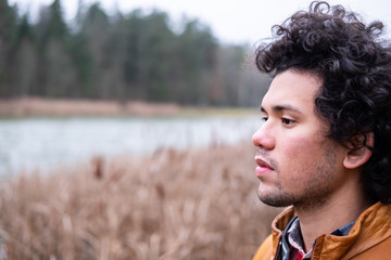 Latin American man at a lake, thoughtful expression 