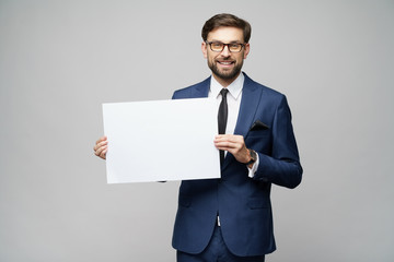 Young businessman holding blank signs over grey background